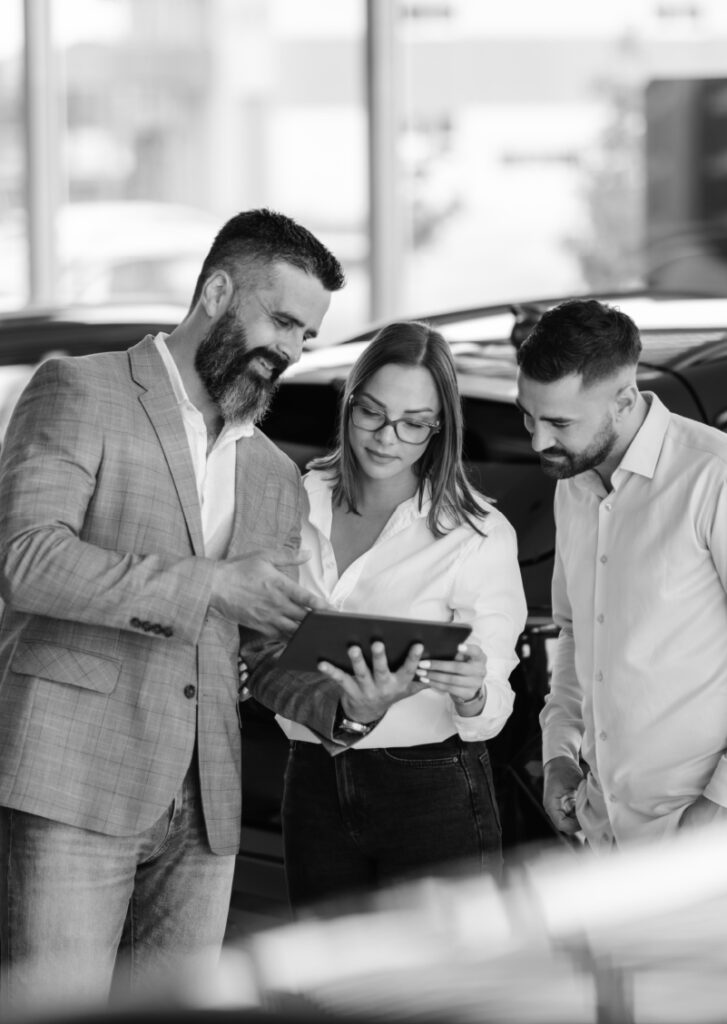 A salesman meets with a couple inside a dealership showroom