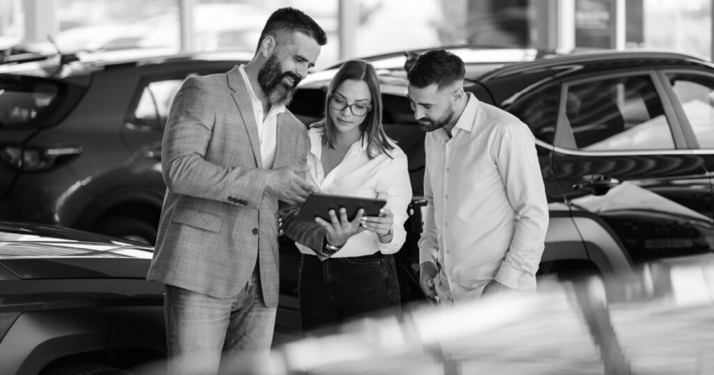 A salesman meets with a couple inside a dealership showroom