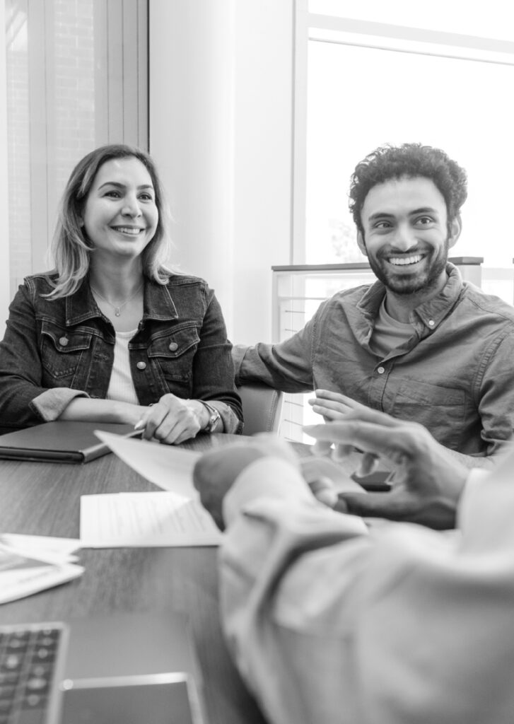 A man and woman sit at a finance desk in a car dealership