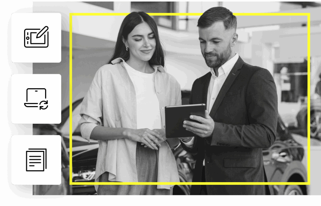 A man and woman look at a tablet computer inside a car dealership showroom